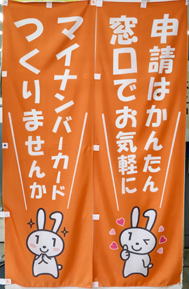 宮崎市様で作成したマイナンバーカード申請に関するのぼりが２つ。右ののぼりの文字：申請は簡単窓口でお気軽に。左ののぼりの文字：マイナンバーカードつくりませんか。