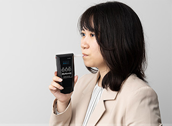 アルコール検知器に息を吹き込む女性
