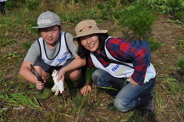 東松島市大曲地区で防災林の植栽活動に参加する円山さん（右）親子